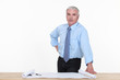 Photo: Grey-haired architect stood by work desk Grey-haired architect stood by work desk