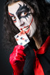 Evil clown with cards in dark room