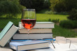 Tisch mit Buecher und Glas Rotwein im Garten.