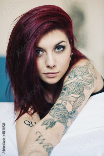 Photo: Sensual portrait of beautiful girl with tattoo lying on bed. Sensual portrait of beautiful girl with tattoo lying on bed.