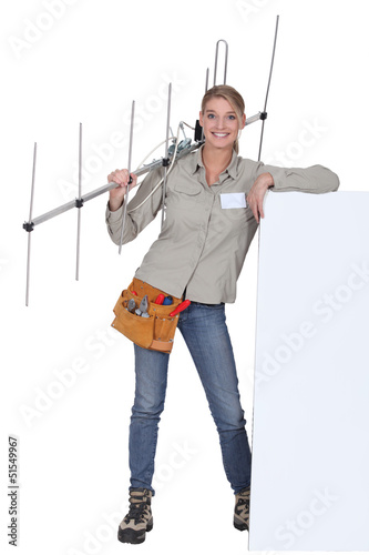 Photo: Woman with an aerial leaning against a blank poster Woman with an aerial leaning against a blank poster