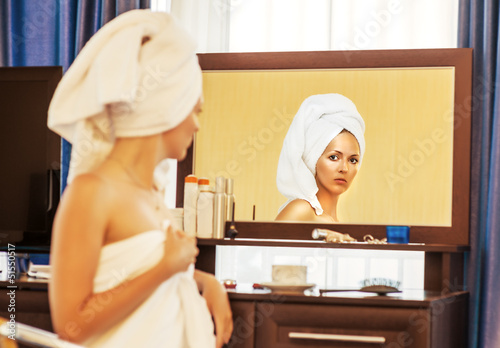 Photo: Woman with towel looking at the mirror Woman with towel looking at the mirror