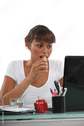Photo: young woman eating a cereal bar young woman eating a cereal bar