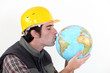 Photo: A construction worker kissing a globe. A construction worker kissing a globe.
