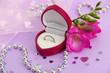 Beautiful box with wedding ring and flower on purple background