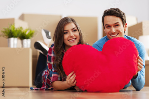 Photo: Young couple holding a heart shape pillow Young couple holding a heart shape pillow