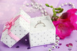 Beautiful box with wedding ring and flower on purple background