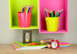 Colorful pencils in pails on shelves on beige background