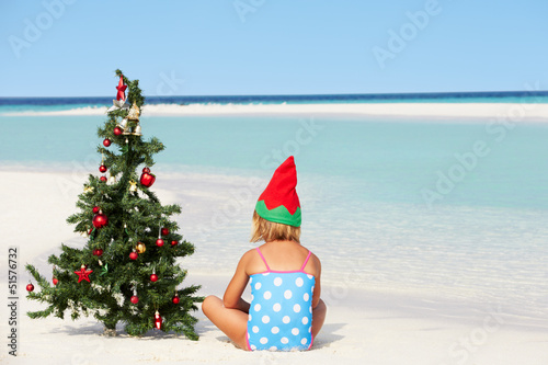 Photo: Girl Sitting On Beach With Christmas Tree And Hat Girl Sitting On Beach With Christmas Tree And Hat