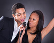 African Couple Singing With Microphone