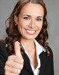 Foto: Businesswoman with thumbs up, over grey Businesswoman with thumbs up, over grey