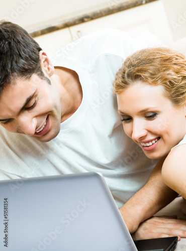 Photo: Cheerful couple with laptop, at home Cheerful couple with laptop, at home