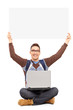 Smiling male student sitting with laptop and holding a blank pan