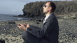 Businessman meditating on the beach, super slow motion