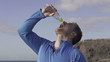 Happy young sportsman drinking water outdoors