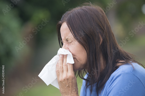 Photo: Woman suffering flu sneezing in tissue Woman suffering flu sneezing in tissue