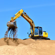 new yellow excavator working on sand dunes