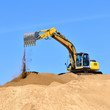 new yellow excavator working on sand dunes