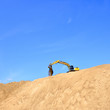 new yellow excavator working on sand dunes