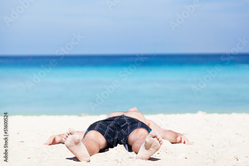 Photo: Man lies on a beach on an ocean coast Man lies on a beach on an ocean coast