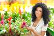 Happy young female florist working while at a greenhouse