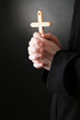 Priest holding cross, on black background