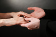 Priest holding woman hands, on black background