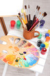 Wooden easel with clean paper and art supplies in room