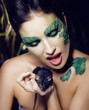 woman with creative make up like snake with rat in her hands