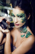 woman with creative make up like snake with rat in her hands
