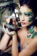 woman with creative make up like snake with rat in her hands