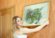 Photo: woman hangs picture on wall at home woman hangs picture on wall at home