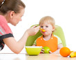 mother spoon feeding her baby girl