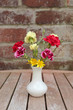 Carnations and celandines in white vase on garden table