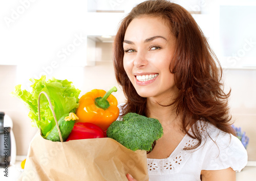 Photo: Happy Young Woman with vegetables in shopping bag Happy Young Woman with vegetables in shopping bag