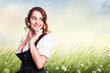 attraktive junge Frau im Dirndl vor Sommerwiese