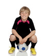 Preteen with a uniform for play soccer sitting on a ball