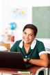 teen girl sitting in classroom using computer