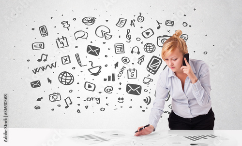 Photo: Young businesswoman with all kind of hand-drawn media icons in b Young businesswoman with all kind of hand-drawn media icons in b
