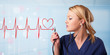 Young nurse listening to abstract pulse with red heart