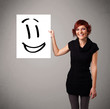 Young woman holding smiley face drawing