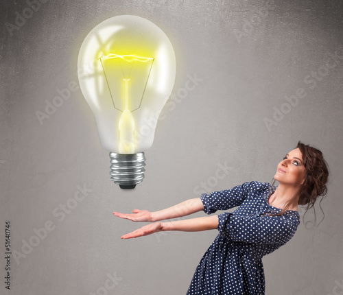 Photo: Beautiful lady holding realistic 3d light bulb Beautiful lady holding realistic 3d light bulb