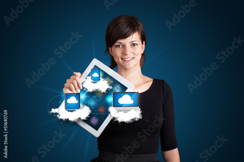 Photo: young woman holding tablet with modern devices in clouds young woman holding tablet with modern devices in clouds