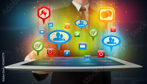 Photo: Businessman presenting modern tablet with colorful social signs Businessman presenting modern tablet with colorful social signs