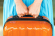 Woman in blue dress holds orange suitcase in hands