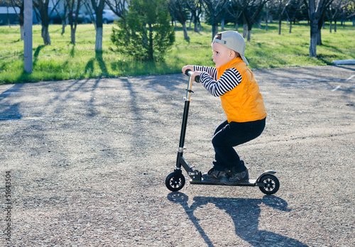 Photo: Cute little boy riding a scooter Cute little boy riding a scooter