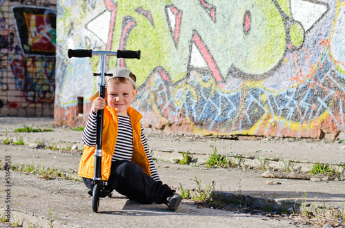 Photo: Cute little boy sitting on his scooter Cute little boy sitting on his scooter
