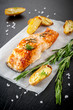 Grilled salmon and baked potatoes on a slate blackboard