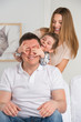 Happy family having fun in the living room: son surprisng his fa