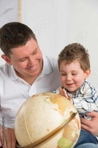 Photo: Father and son looking at globe at home and having fun Father and son looking at globe at home and having fun